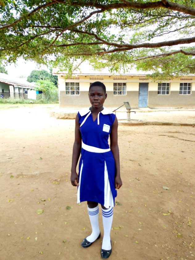 Joyce Awate standing in front of a school building